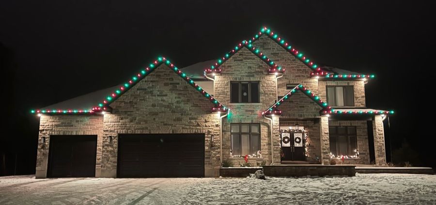 Stone home with Christmas lights installed along the roofline